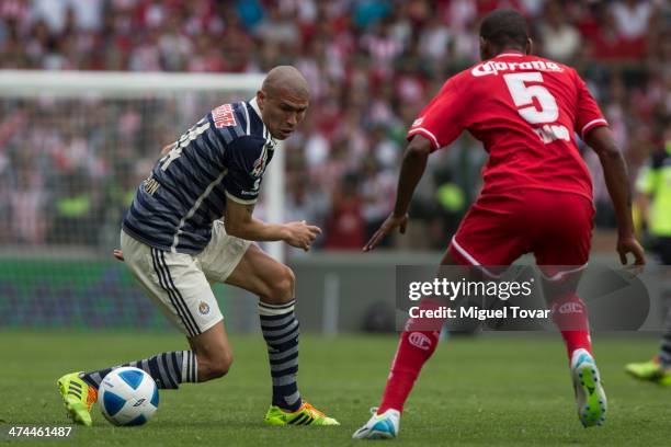 Jorge Enriquez drives the ball as Wilson Tiago of Toluca defends during a match between Toluca and Chivas as part of the eighth round of the Clausura...