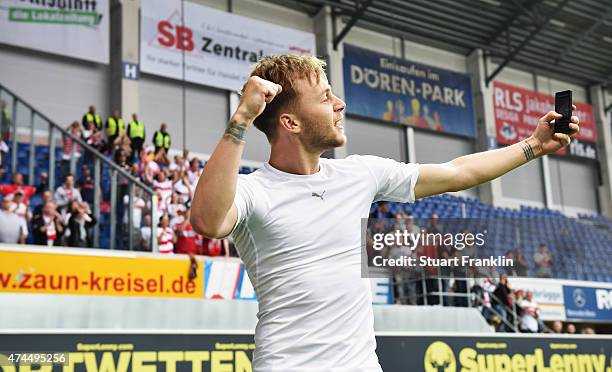 Maxim of Stuttgart celebrates by taking a selfie with fans in the background after staying in the first Bundesliga after winning the Bundesliga match...