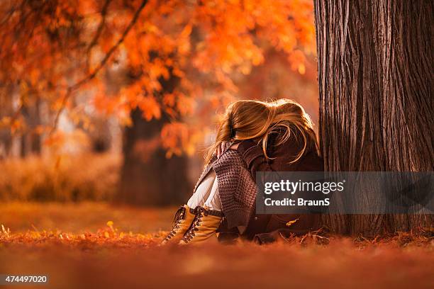 sad woman sitting in the park during autumn day. - autumn sadness stock pictures, royalty-free photos & images