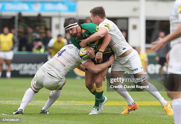 Tom Wood of Northampton is tackled by George Kruis and Owen Farrell during the Aviva Premiership play off semi final match between Northampton Saints...