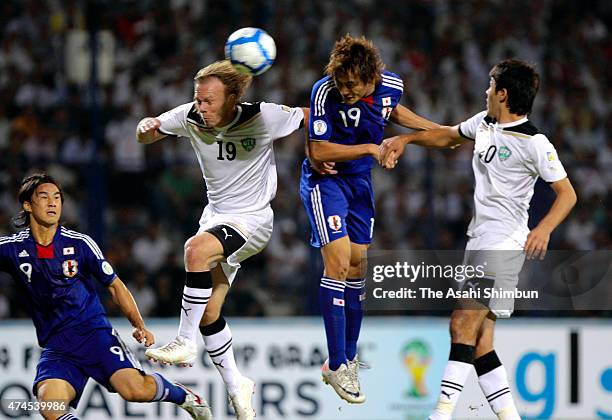 Tadanari Lee of Japan and Vitaliy Denisov of Uzbekistan compete for the ball during the 2014 FIFA World Cup Asian third round group C qualifying...