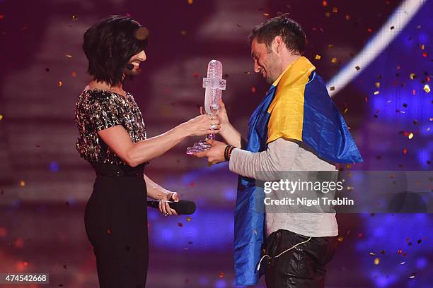 Conchita Wurst hands over the trophy to Mans Zelmerloew of Sweden after winning the final of the Eurovision Song Contest 2015 on May 23, 2015 in...