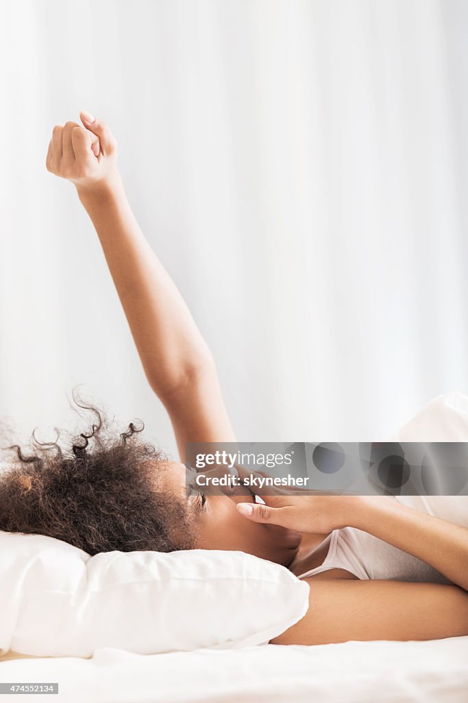 African American woman lying in bed and yawning.