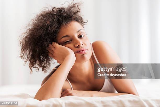 african american femme allongée sur un lit et regardant la caméra. - fatigué photos et images de collection