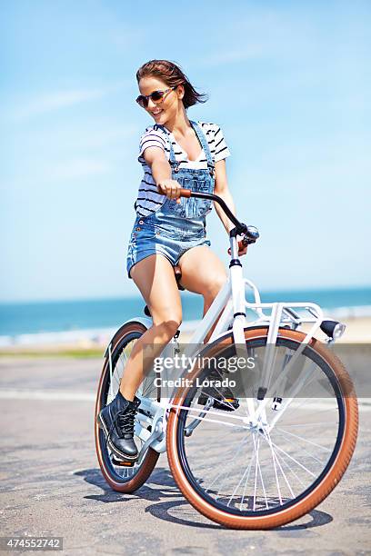 happy young woman riding bike near north sea - turning stock pictures, royalty-free photos & images