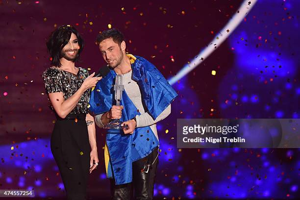 Conchita Wurst hands over the trophy to Mans Zelmerloew of Sweden after winning the final of the Eurovision Song Contest 2015 on May 23, 2015 in...