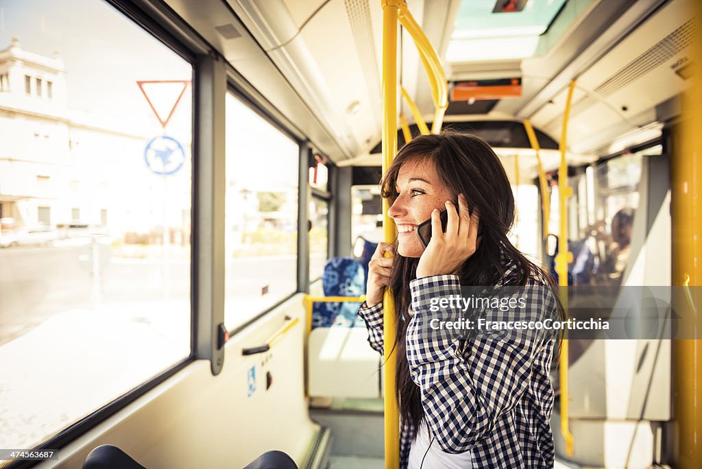 Young happy woman with smart phone on the bus
