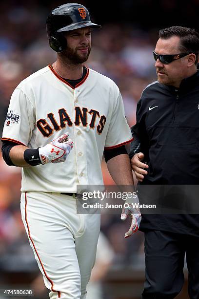 Brandon Belt of the San Francisco Giants is attended to by trainer Dave Groeschner after getting hit by a pitch against the Los Angeles Dodgers...