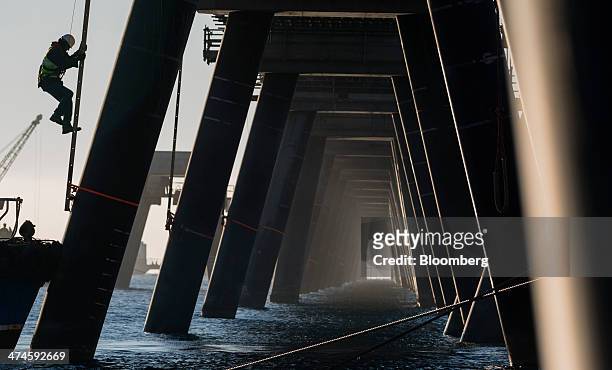 Construction worker walks down a ladder beside a fuel loading jetty in the Mediterranean Sea at the VTTV oil storage terminal, a joint venture of...