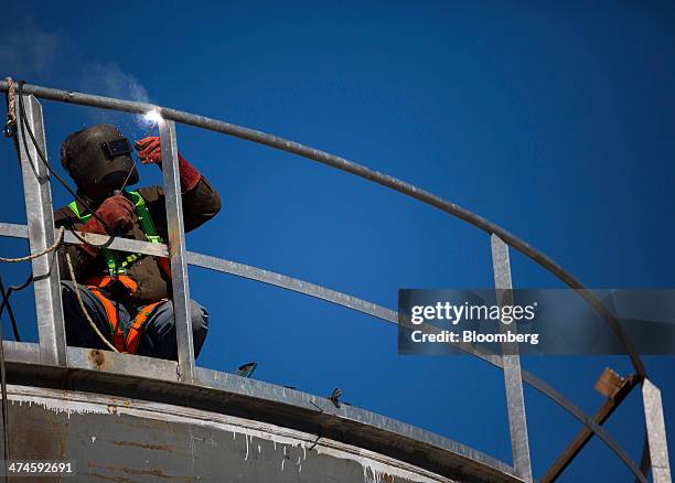 Construction worker welds a rail on top of a fuel storage tank at the VTTV oil storage terminal, a joint venture of Vitol Group and MISC Bhd., in...