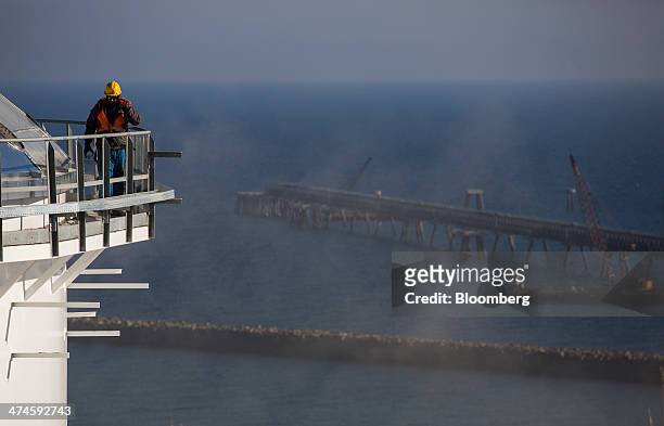 Construction worker stands on a platform on the top of a fuel storage tank over looking a fuel transportation jetty and the Mediterranean Sea at the...