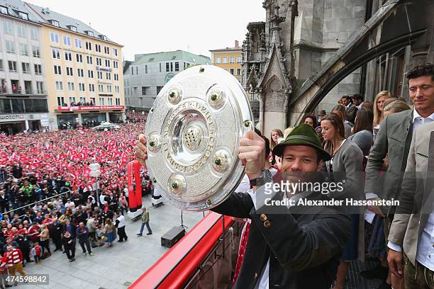 Xabi Alonso of Bayern Muenchen holds the German Championship winners trophy as the team celebrate winning the German Championship title on the town...