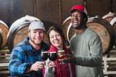 Three people in a microbrewery holding glasses of beer