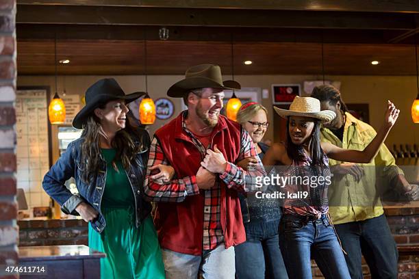 multi-ethnic group of friends dancing in a bar - country and western music stock pictures, royalty-free photos & images