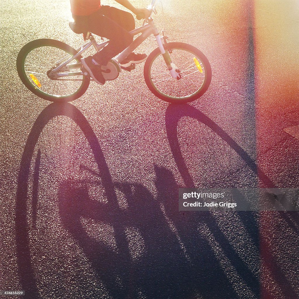 Long afternoon shadow of child riding bicycle