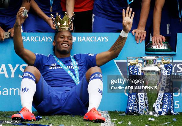 Chelsea's Ivorian striker Didier Drogba wears the crown holding a camera as he poses during the presentation of the Premier League trophy after the...