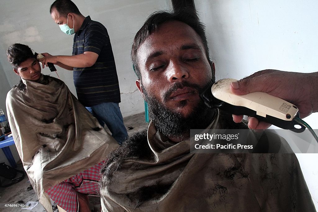 Volunteers help migrant Bangladeshi cut their hair in a...