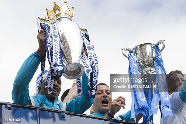 Chelsea's Ivorian striker Didier Drogba holds up the Premier league trophy as Chelsea's English defender John Terry holds up the League cup as they...
