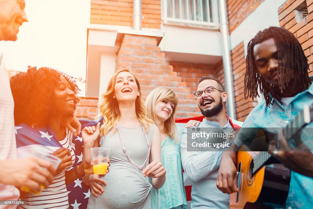 Happy Young People Dancing And Singing At Backyard Party.