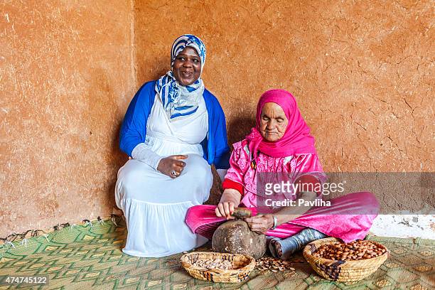 two woman at work for manufacturing argan oil in morocco - argan oil stockfoto's en -beelden