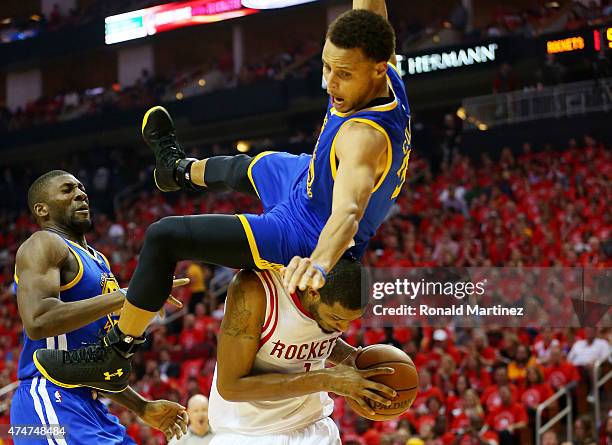 Stephen Curry of the Golden State Warriors falls over Trevor Ariza of the Houston Rockets on his way to an injury in the second quarter during Game...