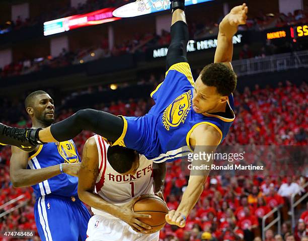Stephen Curry of the Golden State Warriors falls over Trevor Ariza of the Houston Rockets on his way to an injury in the second quarter during Game...