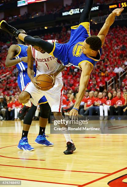 Stephen Curry of the Golden State Warriors falls over Trevor Ariza of the Houston Rockets on his way to an injury in the second quarter during Game...