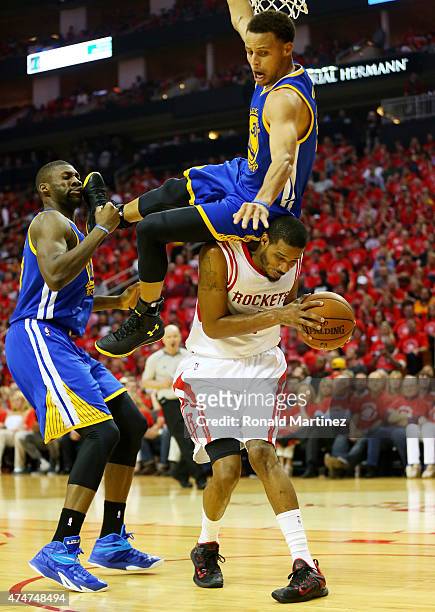 Stephen Curry of the Golden State Warriors falls over Trevor Ariza of the Houston Rockets on his way to an injury in the second quarter during Game...