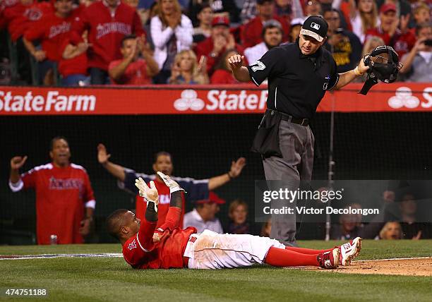 Homeplate umpire Scott Barry signals Erick Aybar of the Los Angeles Angels of Anaheim safe at home plate after a wild pitch by pitcher Tyson Ross of...