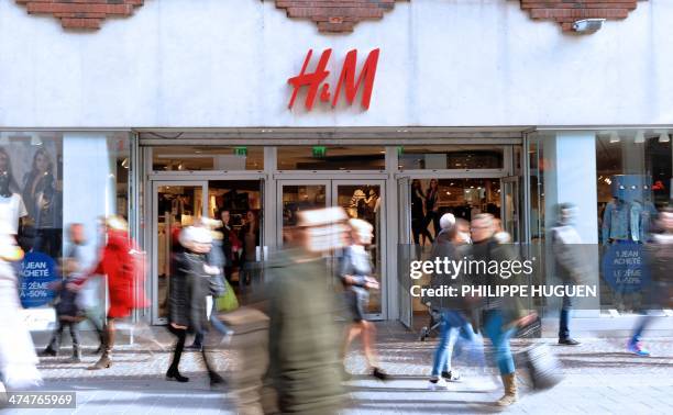 Pepole walk in front of the entrance of a H&M clothing store on February 24, 2014 shows in the French northern city of Lille. AFP PHOTO / PHILIPPE...