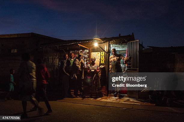 Single electrical light bulb illuminates the exterior of an informal convenience store, also known as a spaza store, in a township in Soweto, South...