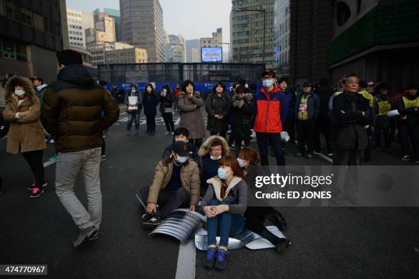 Anti-government protesters sit on a road as they take part in a rally in Seoul on February 25, 2014. South Korean President Park Geun-Hye unveiled a...