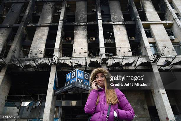 Woman makes a telephone call in front of a burnt out building in Independence Square where dozens of protester were killed in clashes with riot...