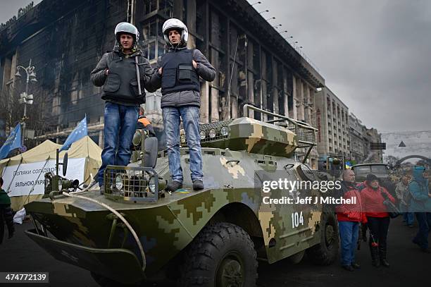 Men stand on top of an armored vehicle, to have his picture take in Independence Square, where dozens of protestors were killed in clashes with riot...