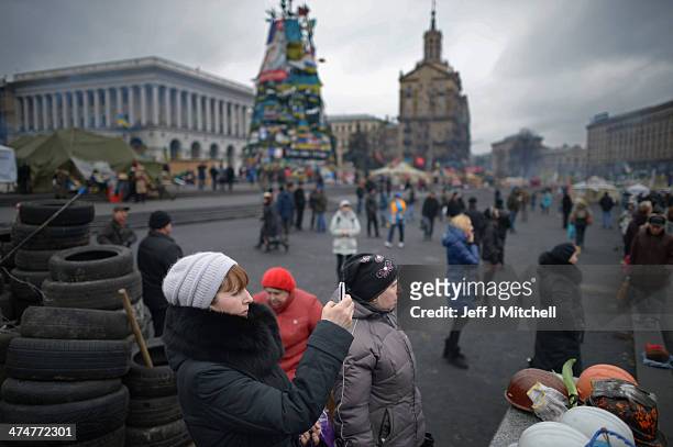 Woman stops to take a photograph in Independence Square, where dozens of protestors were killed in clashes with riot police last week on February 25,...