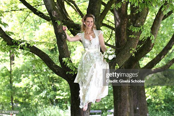 Monica Ivancan, wearing a wedding dirndl by Astrid Soell, poses sitting in a tree during a photo session on May 11, 2015 in Munich, Germany.