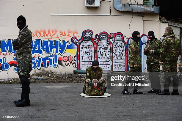 Young men do sit ups next to graffiti in Independence Square where dozens of protestors were killed in clashes with riot police last week on February...