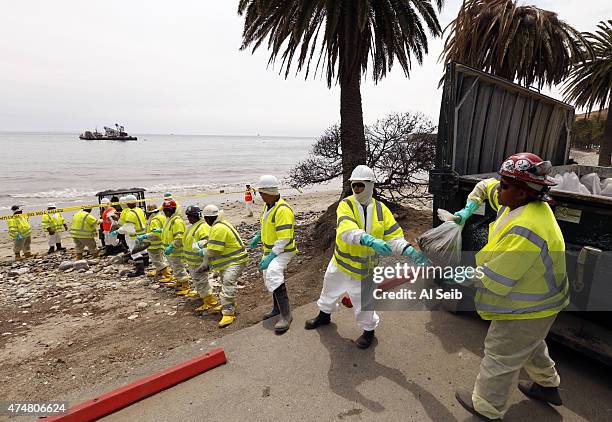 Crews in protective gear form a line to move bags of oiled sand into collection bins at Refugio State Beach May 26, 2015 on the Gaviota Coast west of...