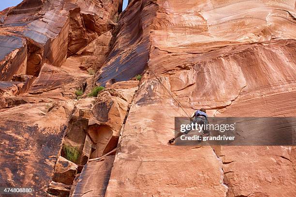 young caucasian man climbing a rock wall near moab - moab utah stockfoto's en -beelden