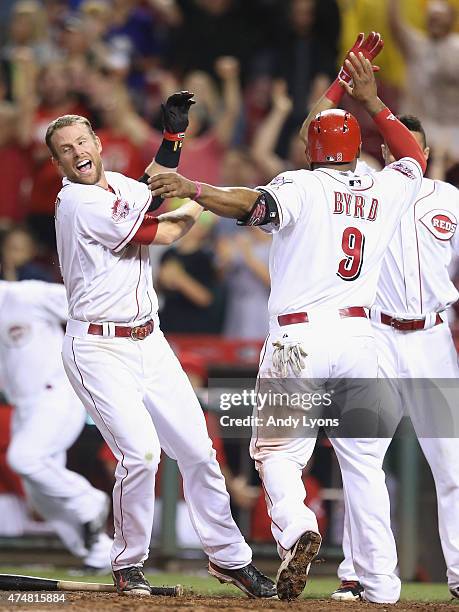 Zack Cozart and Billy Hamilton of the Cincinnati Reds celebrate with Marlon Byrd as he scores the winning run in the 9th inning against the Colorado...