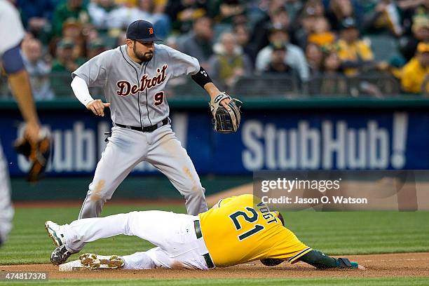 Stephen Vogt of the Oakland Athletics slides into third base after getting hit with a throw to Nick Castellanos of the Detroit Tigers during the...