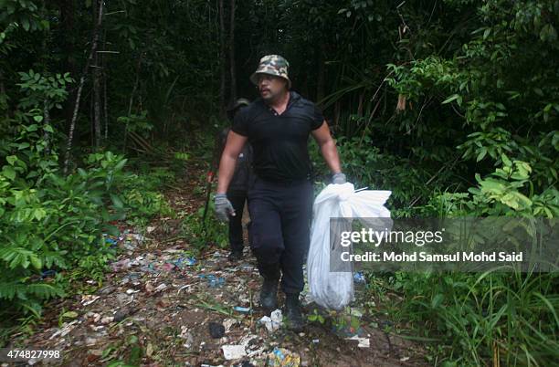 Malaysian General Operations Force police officers carry unidentified human remains down from a mass grave site suspected to be of ethnic Rohingyas...
