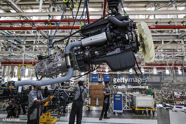 An employee uses a hoist crane to move an engine of a BharatBenz truck on the production line of the Daimler India Commercial Vehicles Pvt....
