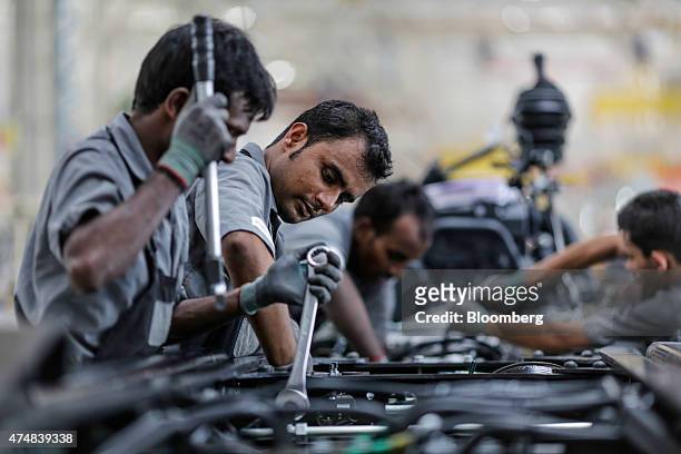 An employee tightens a bolt while working on the chassis and powertrain of a BharatBenz truck on the production line of the Daimler India Commercial...