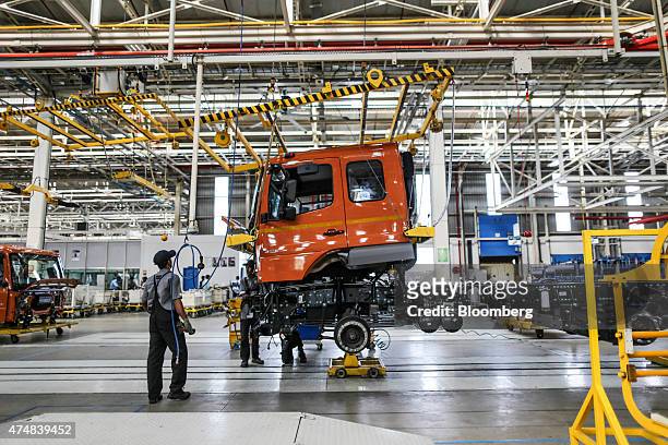 Employees move a BharatBenz truck with a hoist crane on the production line of the Daimler India Commercial Vehicles Pvt. Manufacturing plant in...