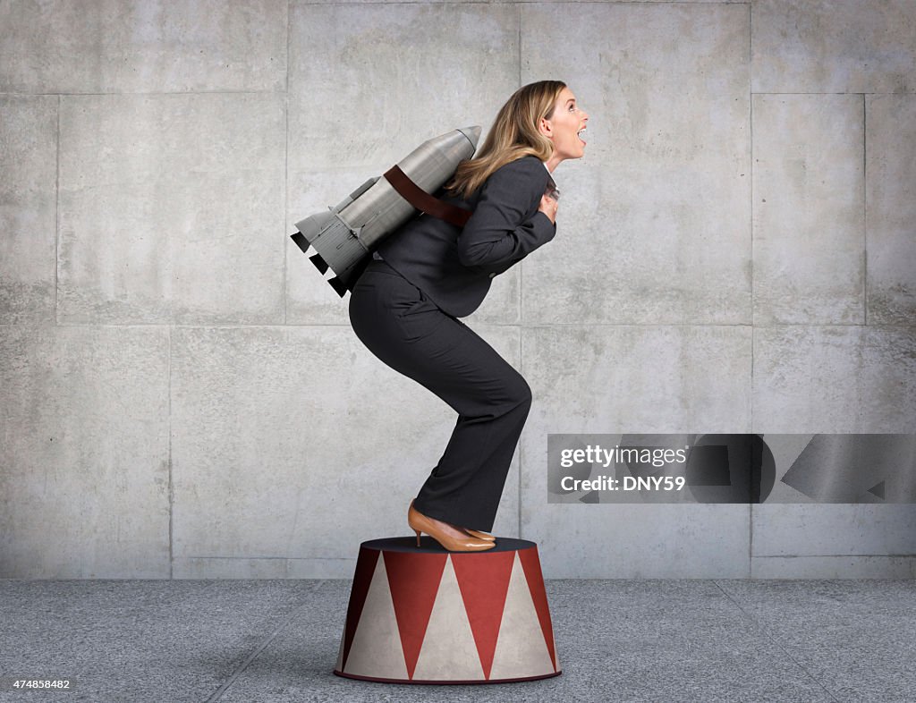 Businesswoman Preparing For Takeoff On Circus Pedestal