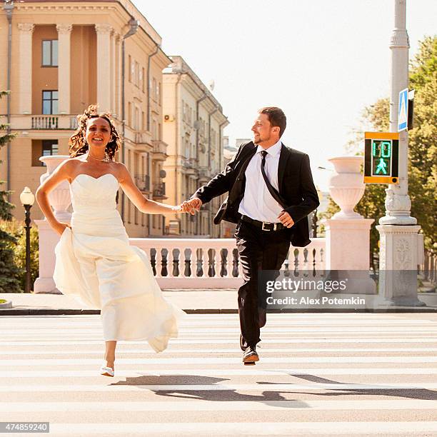 real wedding: bride and groom run across the street - bride running stock pictures, royalty-free photos & images