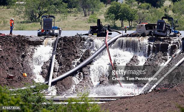 Workers tend to equipment used to pump water from Padera Lake as water pours over a temporary dam on May 27, 2015 in Midlothian, Texas. Officials...