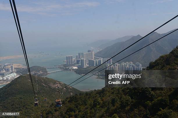 This picture taken on February 23, 2014 shows a line of cable cars with visitors crossing the Tung Chung Bay on way to the Giant Buddha statue and...