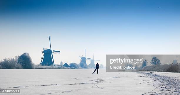 ice-skating man on canal,near windmills kinderdijk winter time - hockey skate stock pictures, royalty-free photos & images